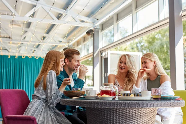 cheerful caucasian friends spending time together in bright cozy time cafe