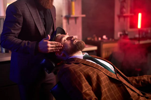 Уверенный мужчина парикмахер готовит клиента к обрезке бороды — стоковое фото