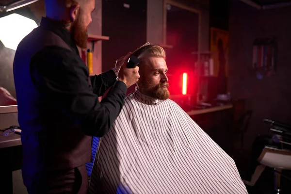 Fiducioso barbiere mster taglia i capelli e la barba degli uomini nel barbiere — Foto Stock