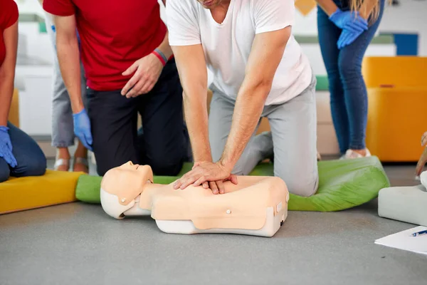 Junger Mann praktiziert CPR an einer Schaufensterpuppe in Anwesenheit von Menschen — Stockfoto