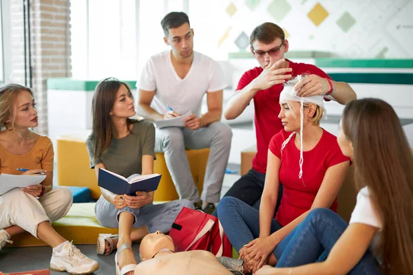 Joven instructor de seguridad masculina confidente enseñar a los estudiantes a vendar la cabeza — Foto de Stock