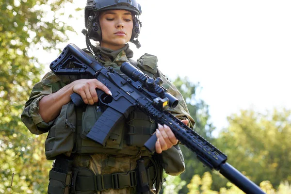 Военная женщина проверяет винтовку в лесу — стоковое фото