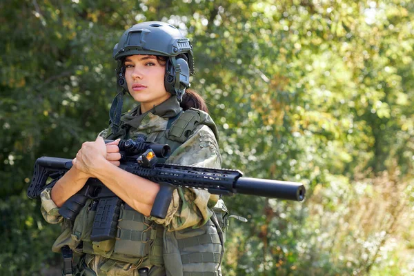 attractive brave military woman with a gun in forest, survival in wild forest