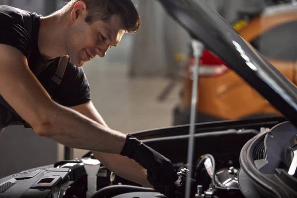 Jovem caucasiano mecânico de automóveis em um serviço de carro, verifica um carro, motor, carburador — Fotografia de Stock