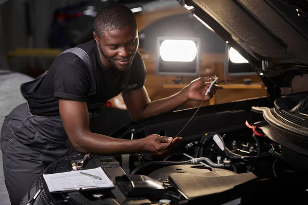 Afrikaans professioneel auto service technicus in de buurt van auto kap repareren en met behulp van auto inspecteren checklist — Stockfoto