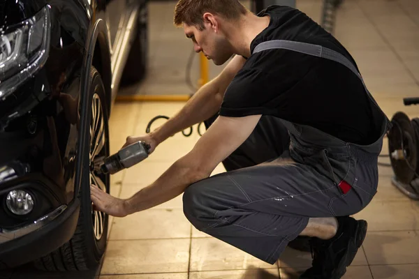 Concentrato professionale meccanico auto uomo ripara una ruota che si è rotto — Foto Stock