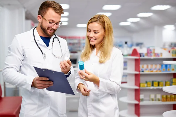 Two caucasian pharmacists are discussing medication, using a digital tablet — Stock Photo, Image