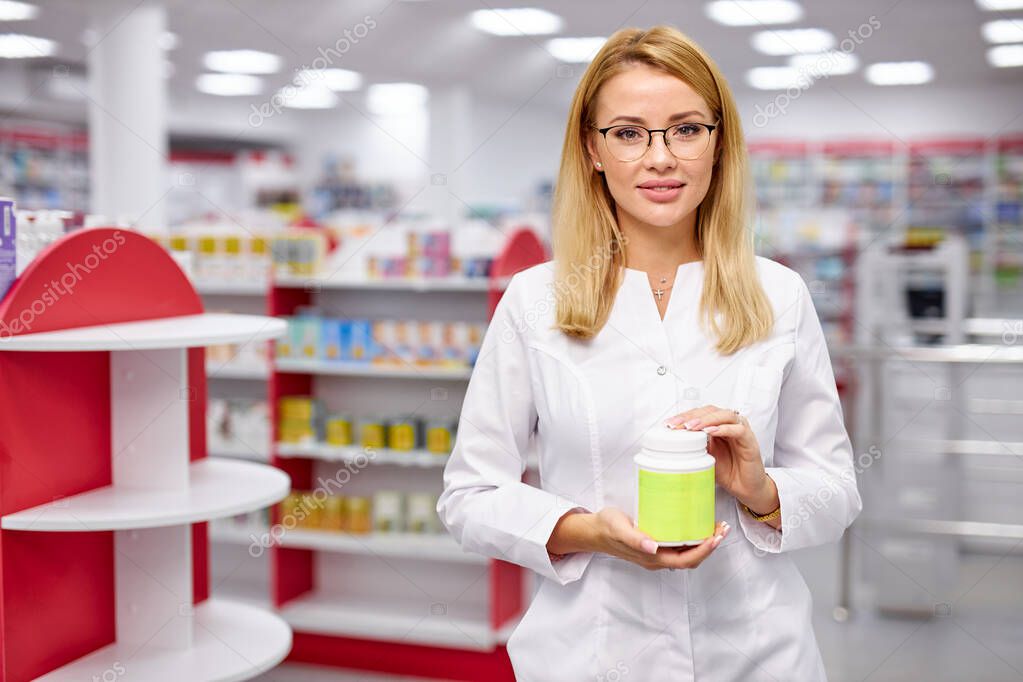 young caucasian female pharmacist is showing medicine box presentation in pharmacy store