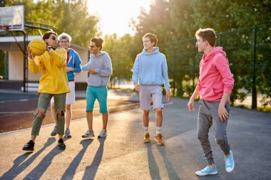 Sportif gençler sokakta basketbol oynayacaklar.