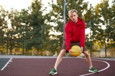 Kafkasyalı genç bir çocuk basketbol topuyla oyunlar oynuyor.