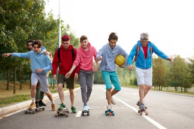 Gündelik giysiler içinde kaykay yapan ve heyecan verici numaralar yapan modern dost canlısı adamlar.