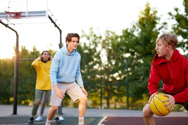 Tonårspojkar som spelar basket på friluftsplan, lekplats och har roligt — Stockfoto