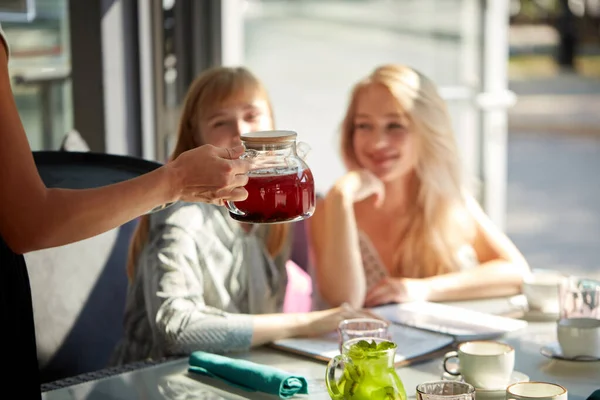 Прибутковий офіціант кафе дарує солодкі напої для двох красивих жінок-клієнтів — стокове фото