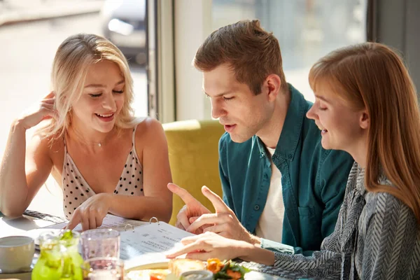 Tři kolegové v kavárně diskutují o jídle v menu — Stock fotografie