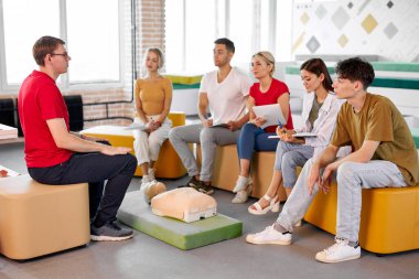 Kendine güvenen erkek eğitmen göster ve ilk acil durum kalp masajı hakkında konuş.