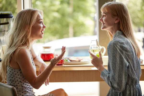 Вид збоку на щасливих блондинки розмовляють і п'ють шампанське в кафе — стокове фото