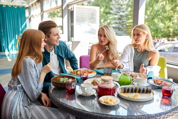 Feliz joven caucásico amigos reuniéndose en la cafetería, sentado a la mesa, charlando, hablando — Foto de Stock