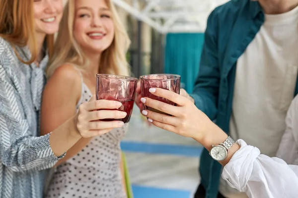 Grupo de jóvenes amigos tintineo vasos en la cafetería — Foto de Stock