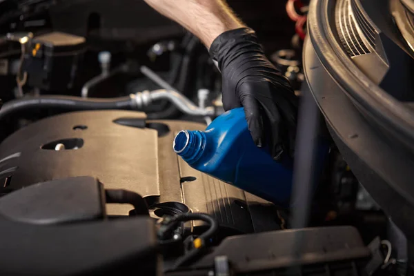 Hombre mecánico en guantes verter aceite en el motor del coche, primer plano — Foto de Stock