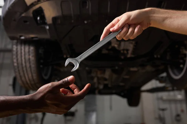 Vista parcial de los mecánicos de automóviles irreconocibles con llave en el taller de reparación — Foto de Stock