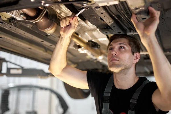 Samec mechanik pracuje na vozidle v autoservisu, sám — Stock fotografie