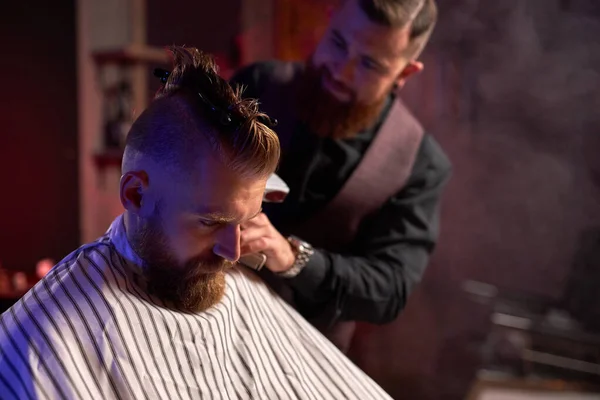 Acconciatore maschile sicuro tagliare i capelli all'uomo elegante elegante seduto nel salone — Foto Stock