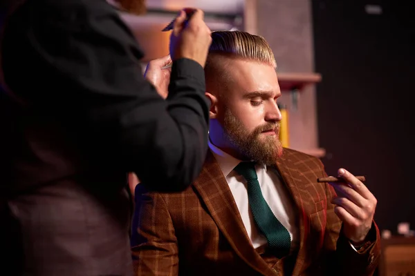 Hairstylist cutting hair to business man smoking in salon — Stock Photo, Image