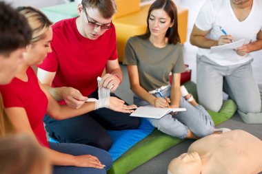 Erkek eğitmen bir eli nasıl doğru şekilde bandajlayacağını gösterir.