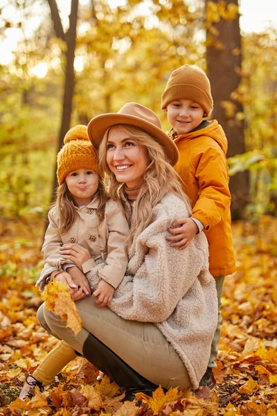 Wanita dewasa berambut pirang dengan anak-anak di hutan musim gugur — Stok Foto