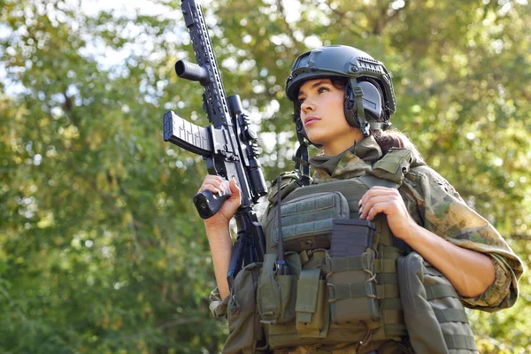 Stark modig kvinnlig armé soldat med gevär kulspruta står i skogen — Stockfoto