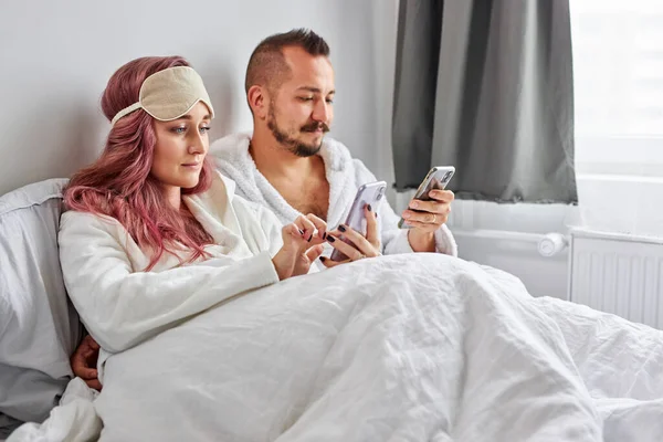 Couple détendu utiliser téléphone mobile couché sur le lit ensemble — Photo
