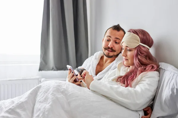 Pareja casada con smartphones en pijama en su cama — Foto de Stock