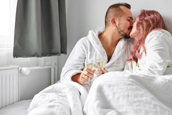 Heureux beau couple caucasien homme et femme portant blanc housecoat, boire du vin mousseux — Photo