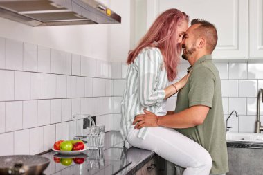 Mutfakta kucaklaşan romantik çiftin yan görüntüsü.