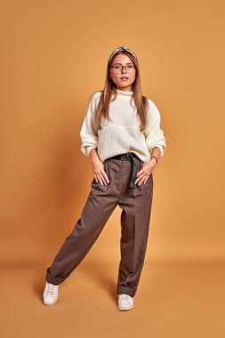 Gözlüklü kadın kameraya özgüvenle bakıyor.