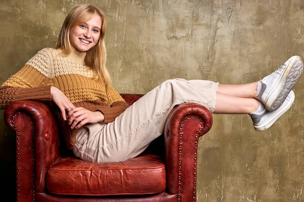 가죽 소파에 앉아 웃고 있는 금발 코카서스 여성 — 스톡 사진