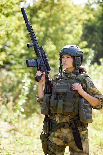 Joven militar caucásica sostiene un arma en su mano en la naturaleza — Foto de Stock