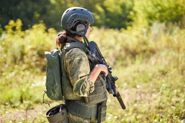 Jovem caucasiano militar mulher segura uma arma em sua mão na natureza — Fotografia de Stock