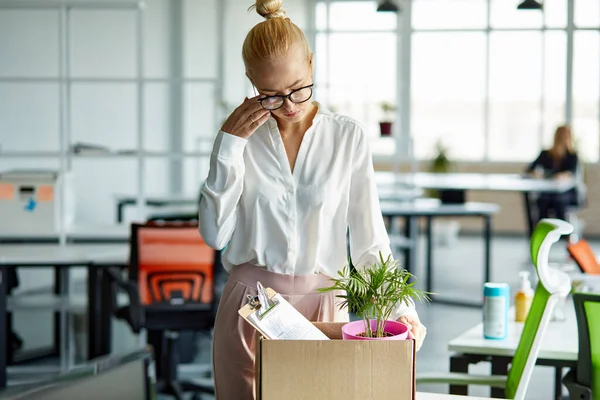 sad dismissed female worker is taking her office supplies from office