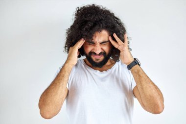 angry arabic male is having mad expressions, squeezing head with hands pissed of people around