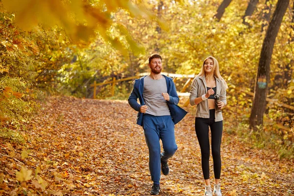 Vrolijke vrienden rennend in het herfstbos of park — Stockfoto