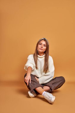 Sıcak gömlekli kendine güvenen bir kadın yerde oturuyor.