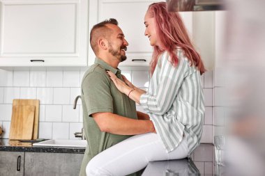 Sevecen, genç ve güzel bir çift modern, rahat, beyaz bir mutfakta öpüşüyor.