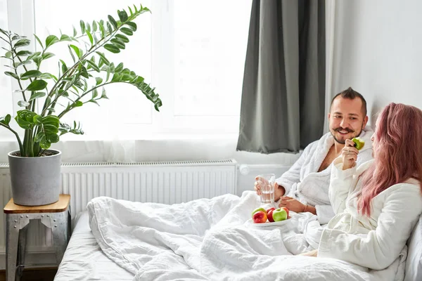 Cheerful couple have breakfast on bed — Stock Photo, Image