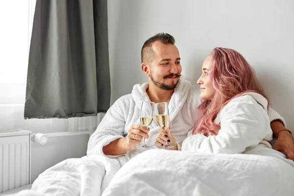 Jovem casal caucasiano homem e mulher vestindo branco housecoat, beber espumante vinho — Fotografia de Stock