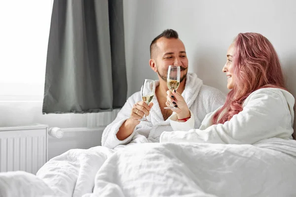 Piękna para mają romantyczny czas na łóżku picie szampana — Zdjęcie stockowe