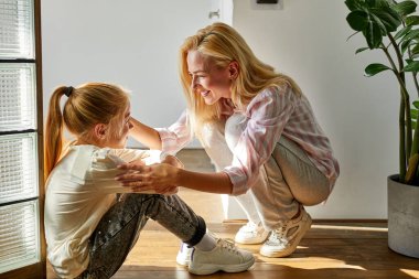 İyimser kız ve anne yerde keyifli konuşuyorlar.