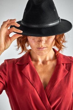 Kendine güvenen zarif bir hanımın portresi. Elbise ve şapkayla aşağıya bakıyor.