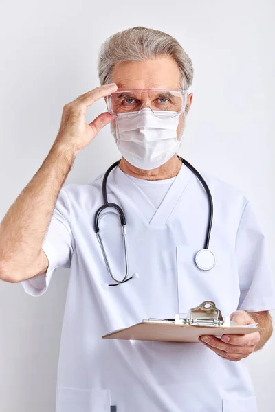 Elderly male doctor wearing goggles, face protective mask for protection from virus disease — Stock Photo, Image