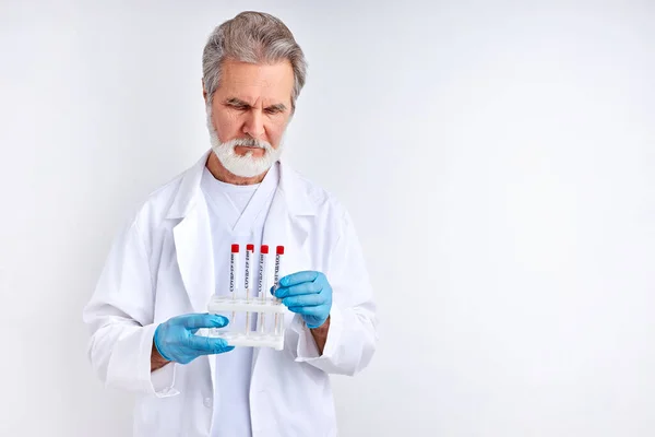 Starszy lekarz badający, badający testy na obecność koronawirusów w probówce — Zdjęcie stockowe
